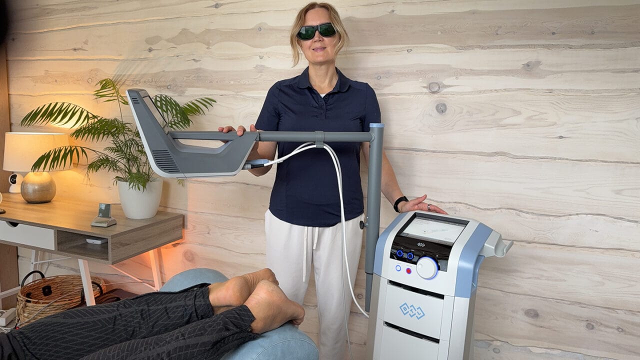 Fysioterapeutti antaa HILT-laserhoitoa asiakkaalle