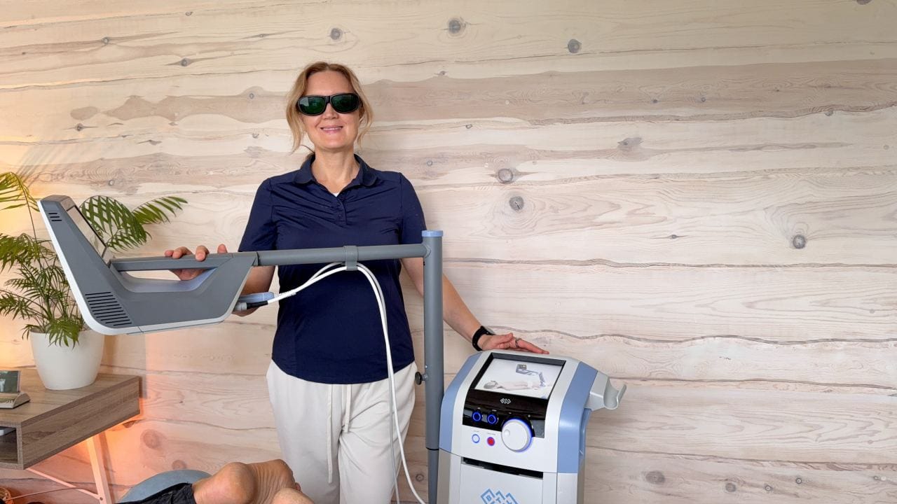 Fysioterapeutti valmistelee HILT-laserhoitoa asiakkaalle.