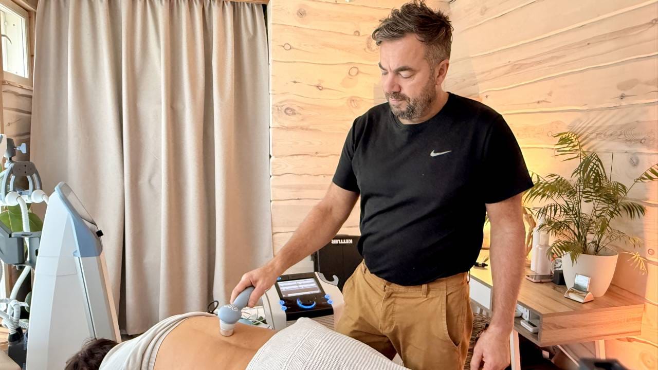 Fysioterapeutti antaa asiakkaalle ultraäänihoitoa selän alueelle.